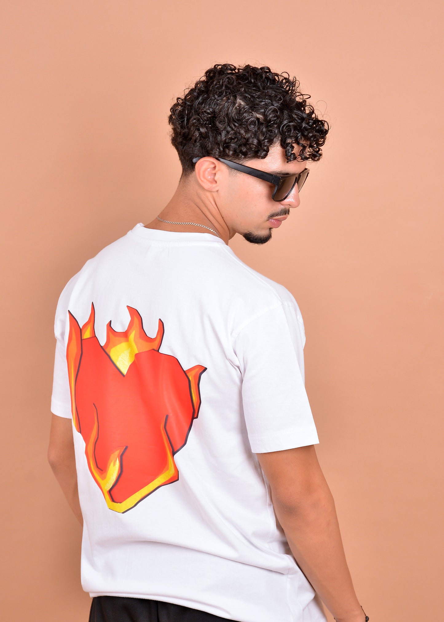 Man wearing a white t-shirt with a red and yellow graphic on the back against a beige background